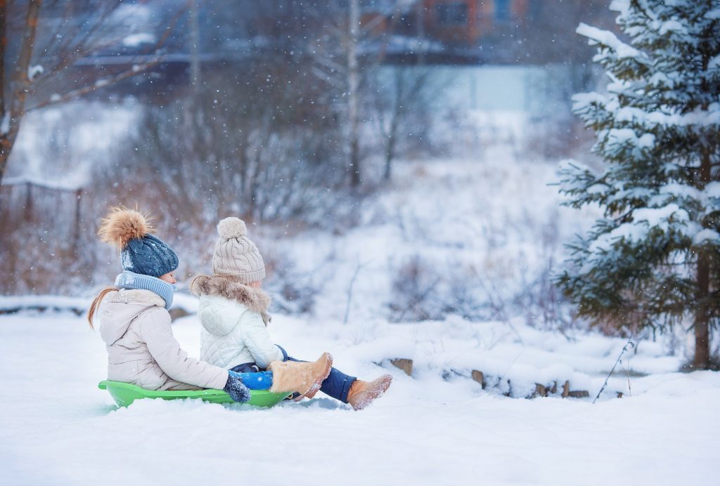Little adorable girls enjoy a sleigh ride. Child sledding. Children play outdoors in snow. Family