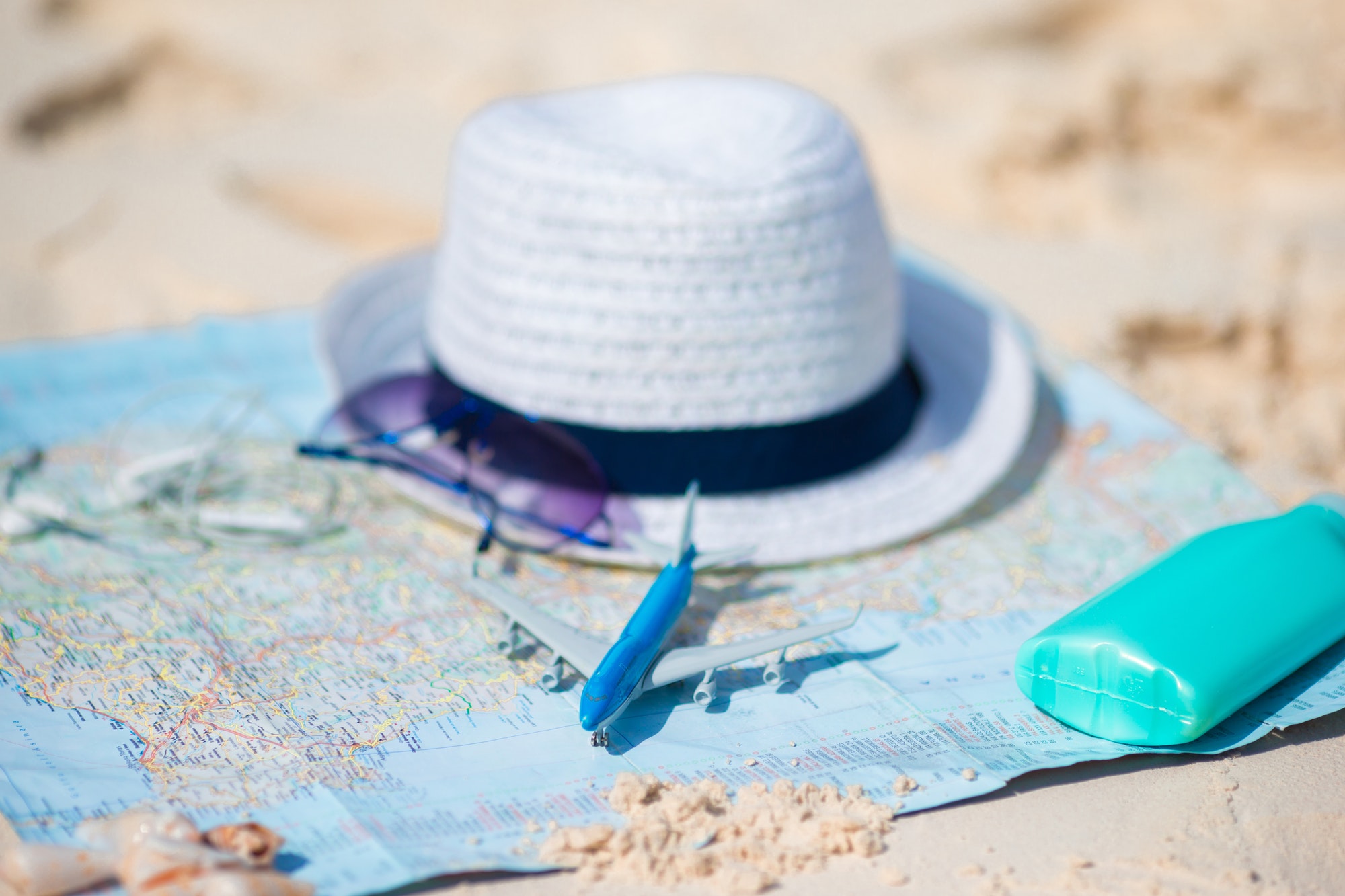 Traveling concept. Hat, suncream, sunglasses on a map of the world
